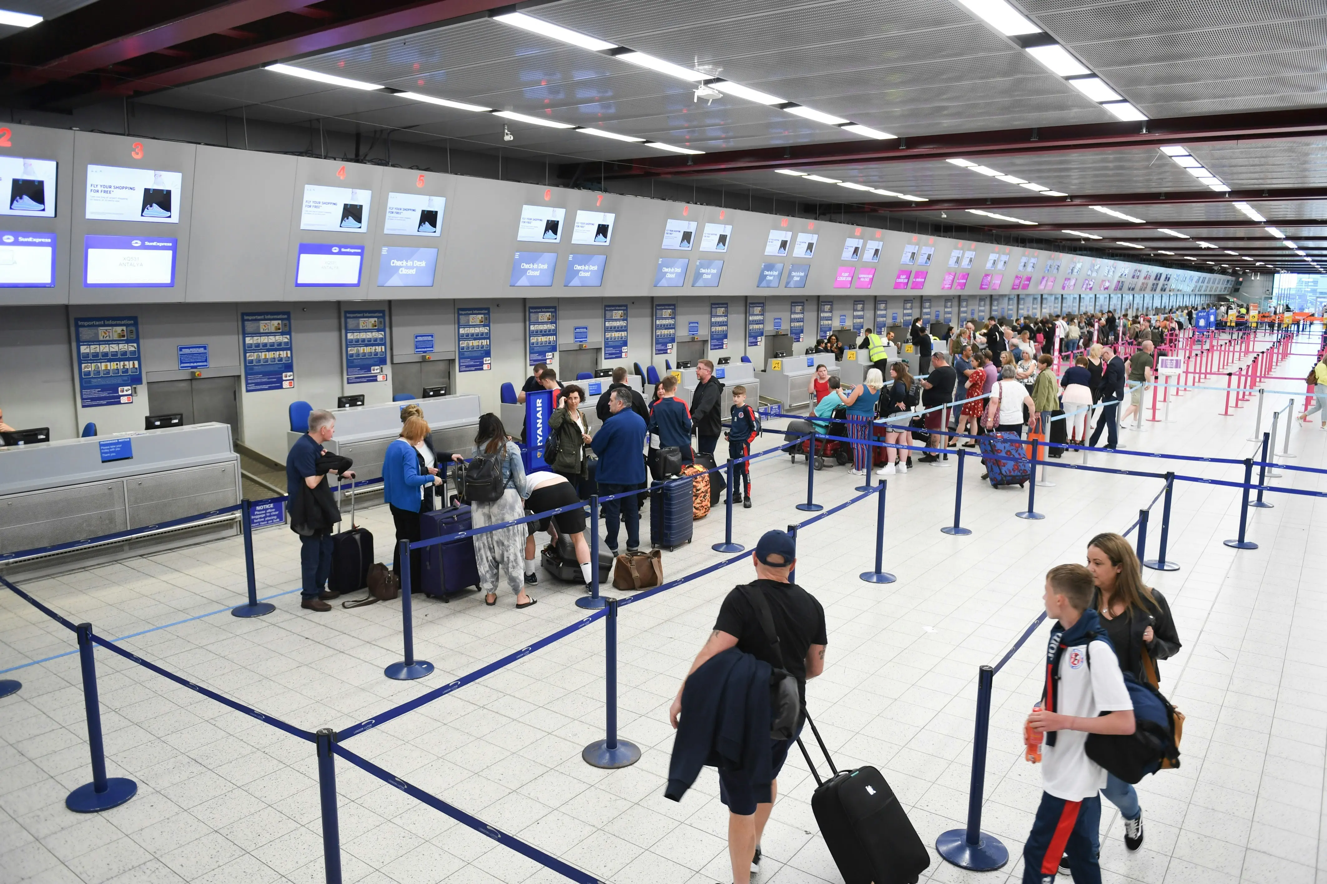 Passengers at airport check-in desks in a busy terminal