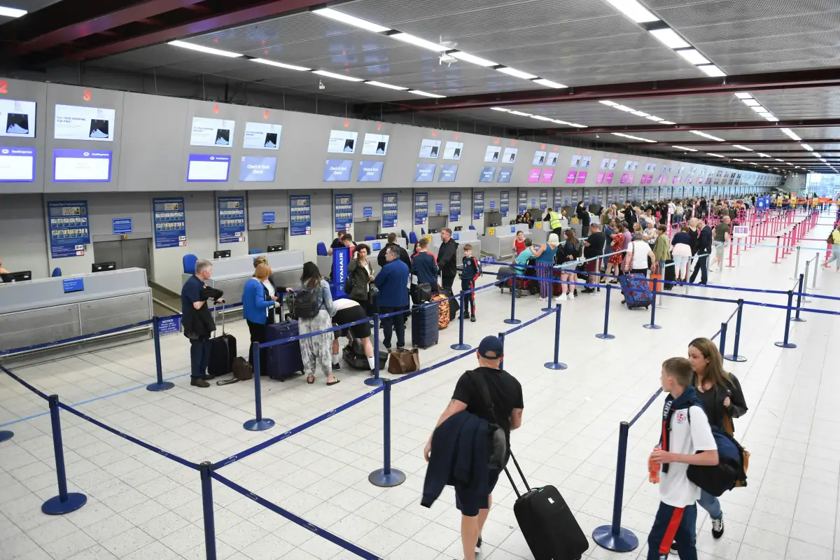 Passengers at airport check-in desks in a busy terminal